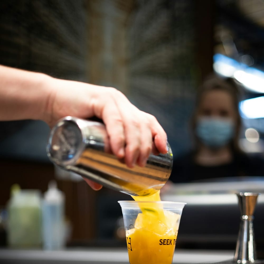 A vibrant fresh juice being poured into a glass to order at the bar