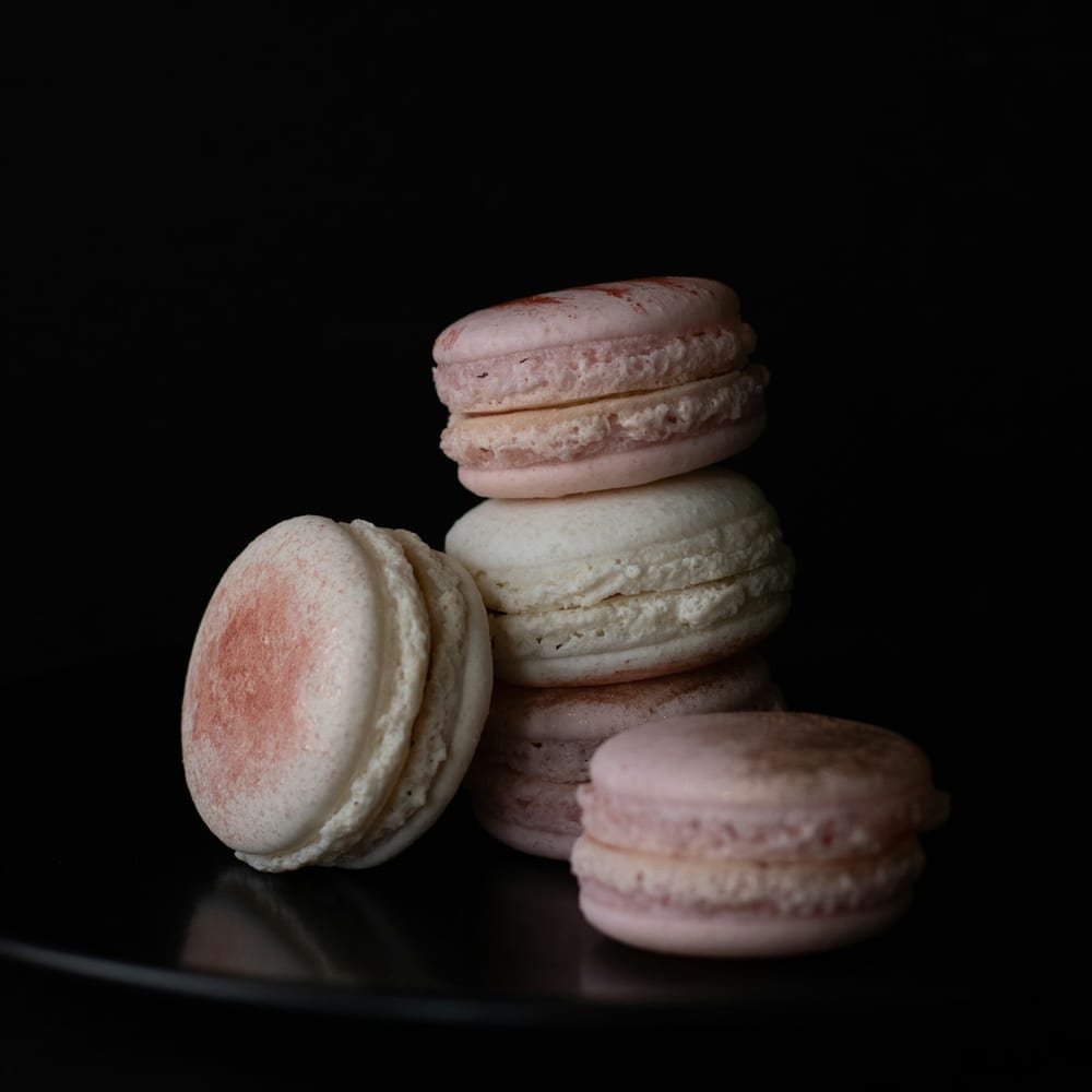 A row of rose macarons with crystallised rose petals on a slate board
