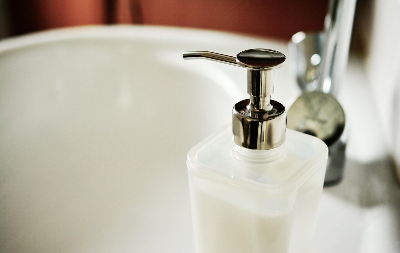 A frosted glass soap dispenser with a chrome pump, filled with white liquid
