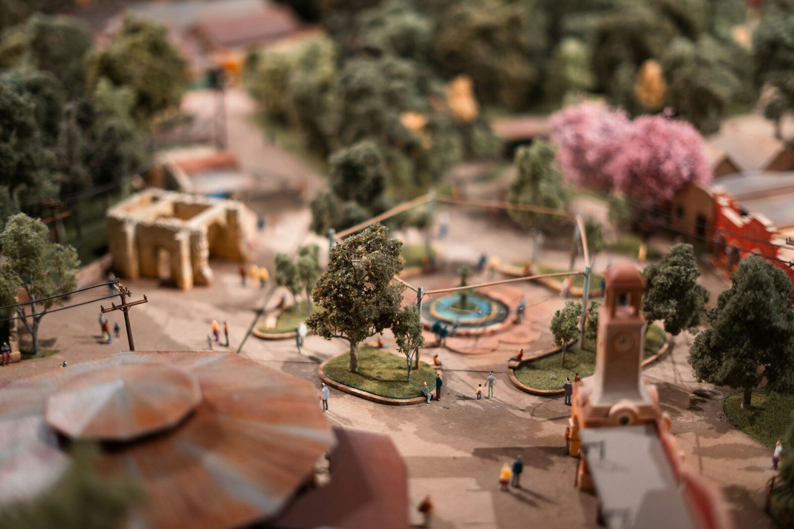 A detailed, fully painted miniature model of a town with trees, a fountain and tiny figures