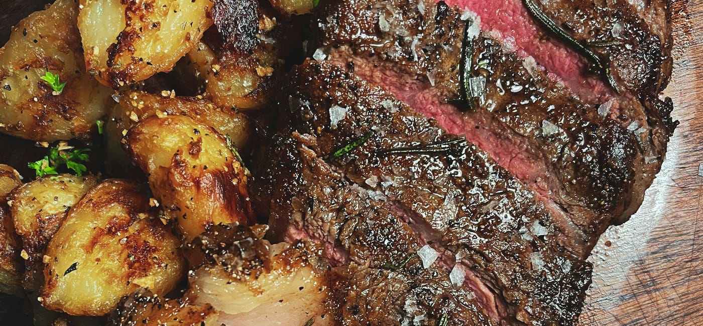 Perfectly seared dry-aged ribeye on a cast-iron plate with au jus