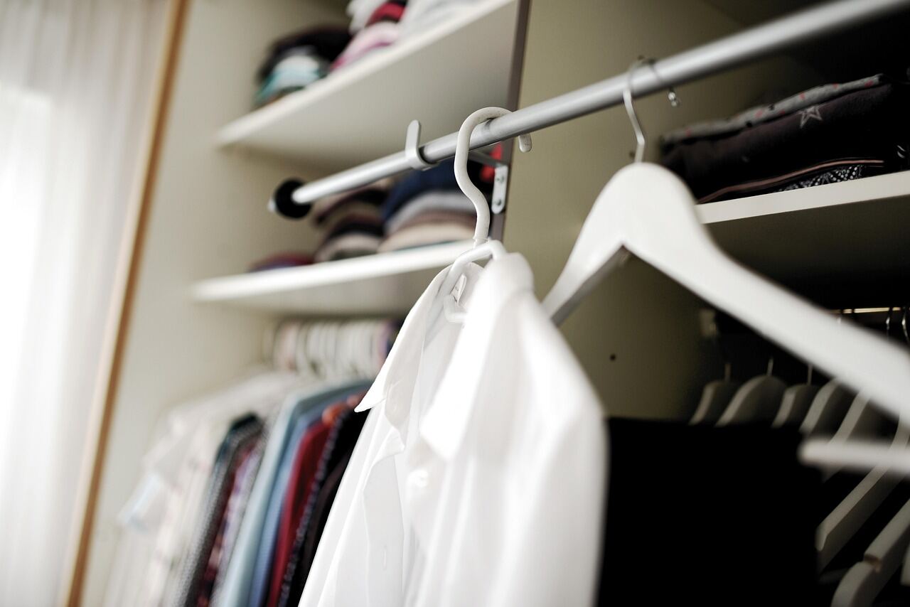 A row of coats and garments hung on a wardrobe rail in a dressing room