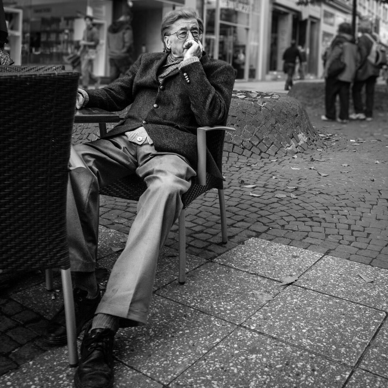 A man in a structured wool overcoat photographed in black and white on a city street
