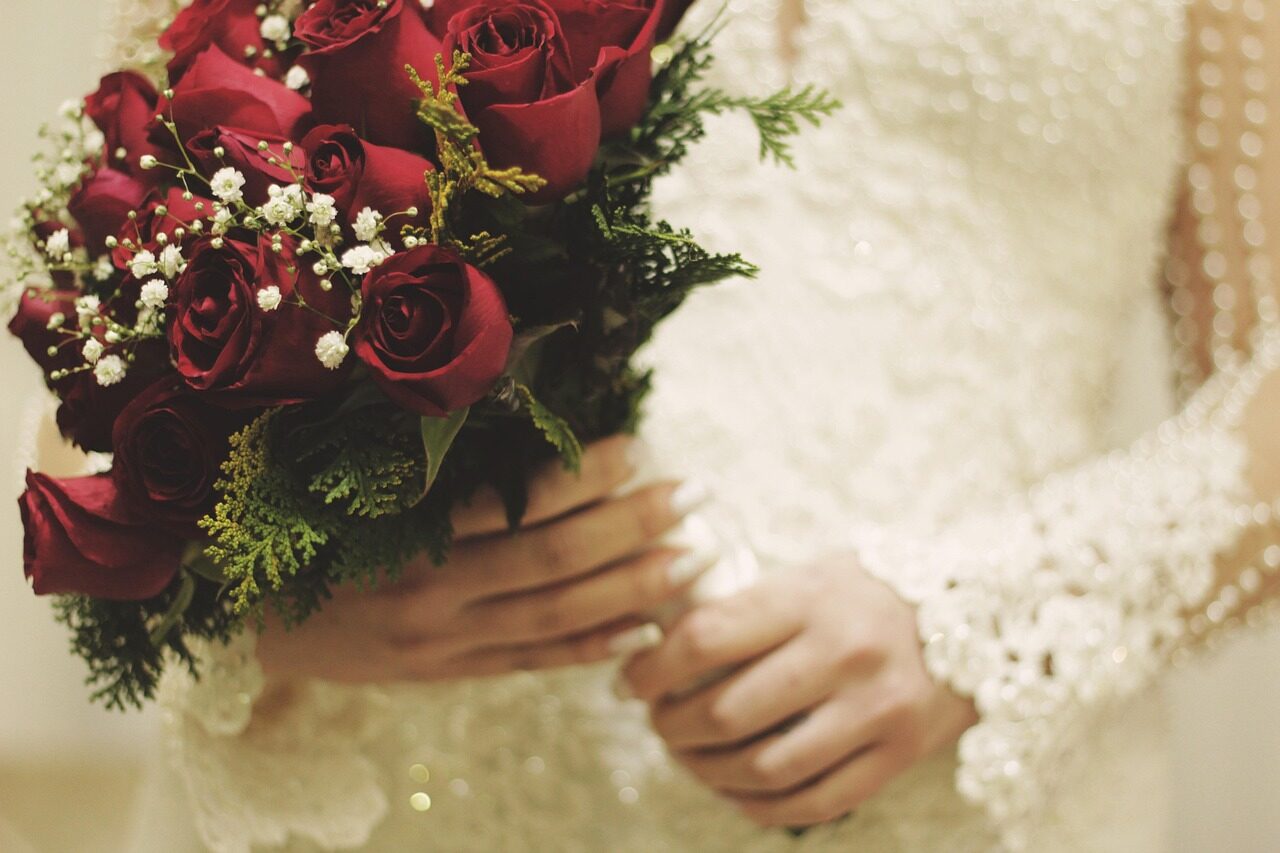 A bouquet of deep red roses held against the front of the dress
