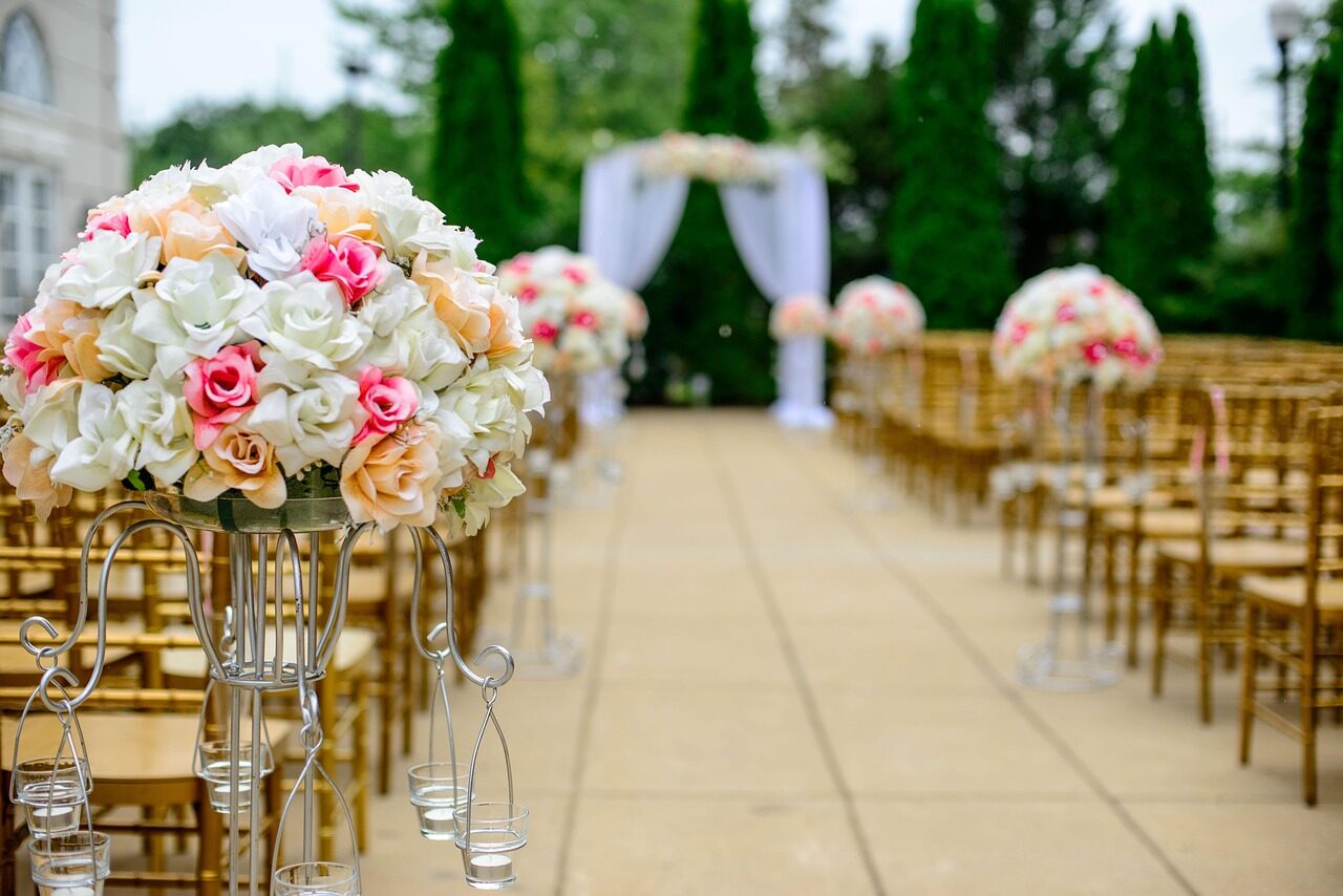 A tall floral arrangement beside gold chairs at the head of the aisle