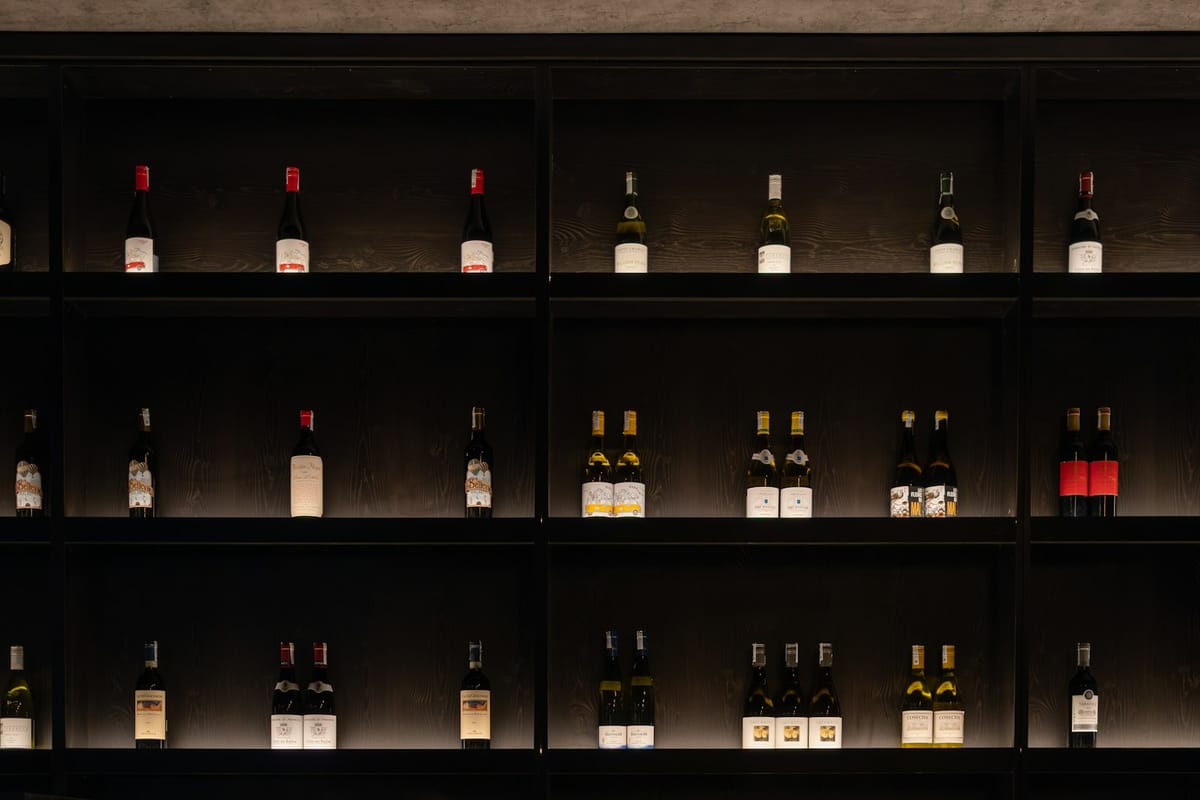 Wine cellar with stone walls and old wooden wine racks receding into warm amber light, bottles resting horizontal