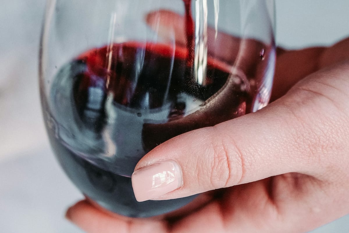 Close-up of a sommelier pouring a translucent red wine from a decanter, hands and bottle in soft gold light