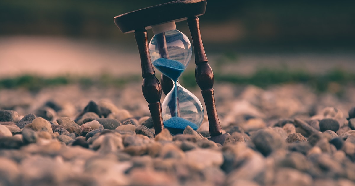 Selective focus photo of brown and blue hourglass on stones