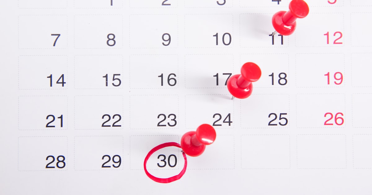 A calendar with red push buttons pinned to it