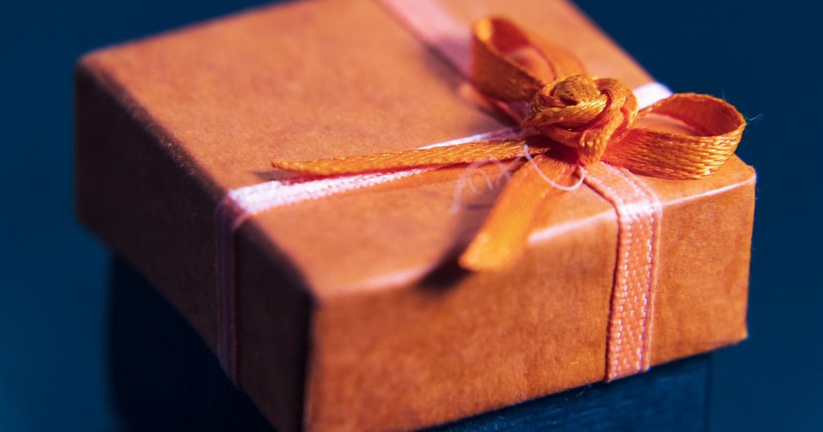 An orange wrapped gift box with a bow