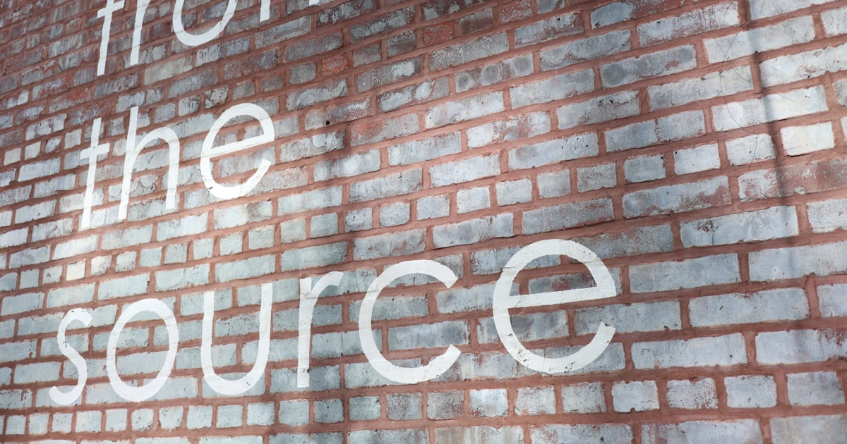 A brick wall with the words from the source painted on it