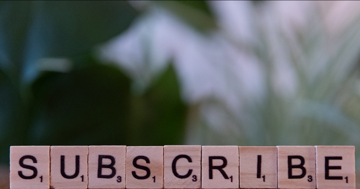 A wooden block spelling subscribe on a table