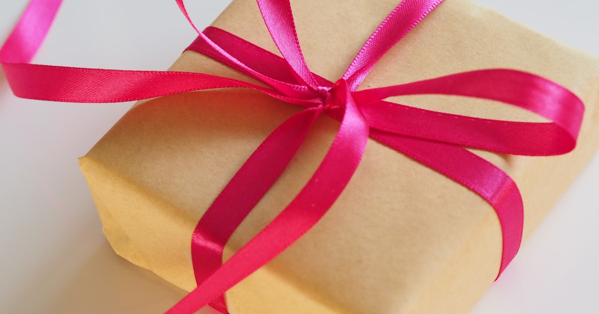 A brown gift box with a pink ribbon